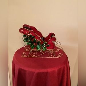 Metal sleigh with holly, gold colored runners & blue & green interior.